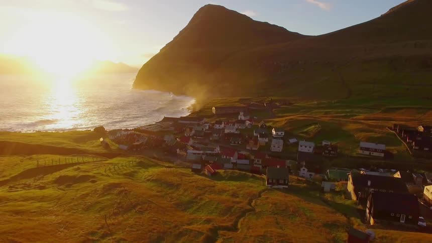 Houses sit below a cliff next to the water