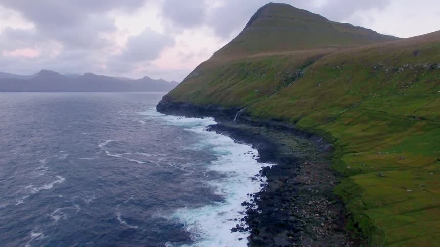 Looking down the coastline as the ocean's white waves crash onto the rocks
