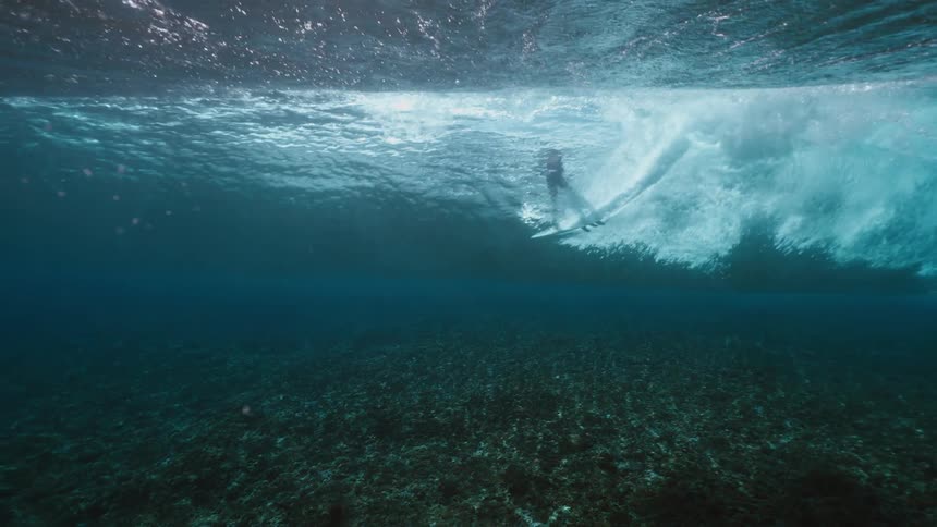 An incredible underwater slow-motion view of a surfer carving a pristine turquoise wave