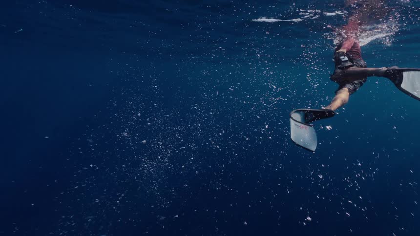 A mesmerizing slow-motion underwater view of a diver's fins creating a cloud of air bubbles in the deep blue ocean