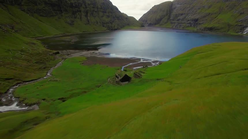 A creek runs toward a lake and past a cabin