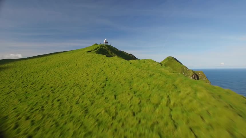Aerial view of grassy mountain top next to the sea