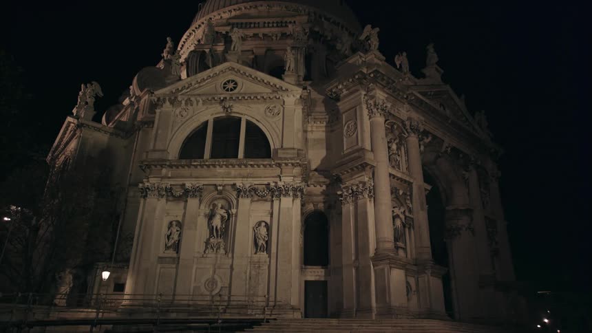 A city building with stone statues is shown at night