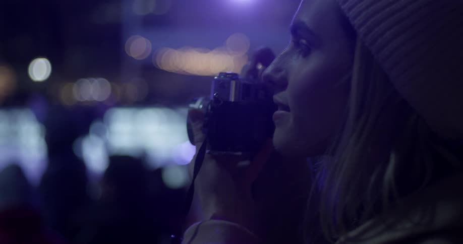 A woman takes a photograph at night