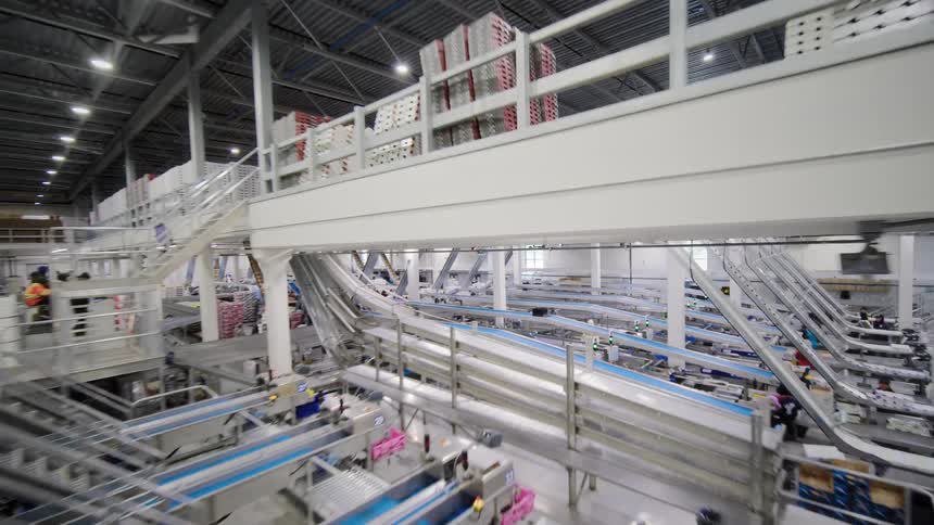 A slow pullback shot reveals the impressive scale of a modern, multi-level automated warehouse with complex conveyor belt systems