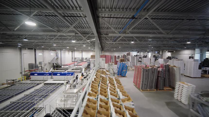 A wide aerial pan reveals the vast operations of a modern, automated industrial food packing and distribution warehouse