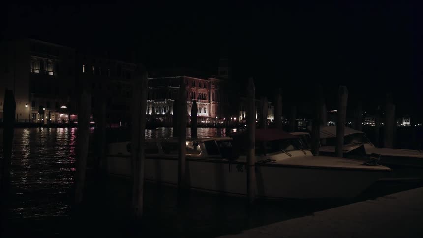 Boats bob and float at dock in a canal at night