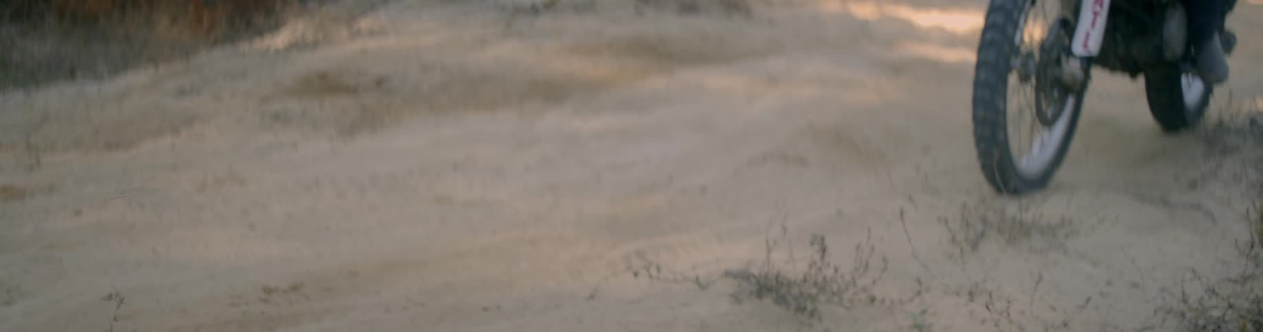 Dirt bike rolling through a sandy area