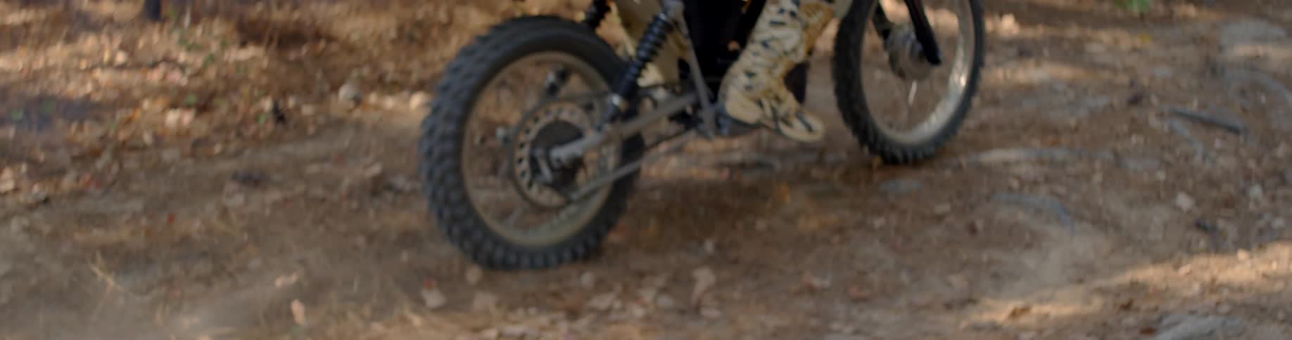 A person rides a dirt bike through a forested area