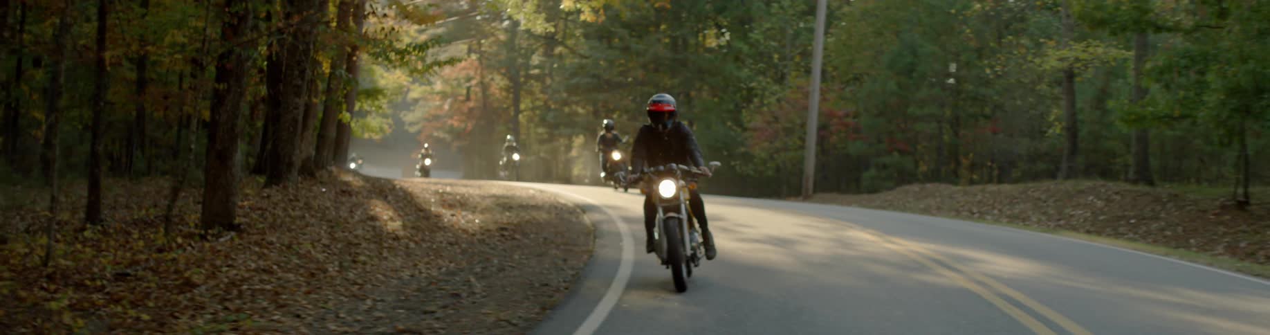 Motorcyclists ride on a forest road