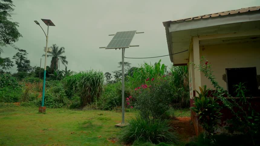 A stationary shot shows solar panels providing green energy in a lush, rural area on a cloudy day