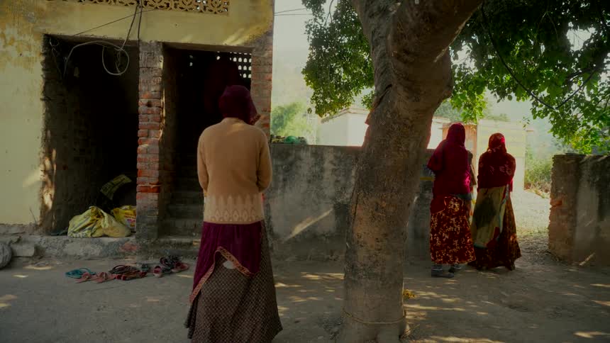 Indian women wearing traditional clothing gather together in a rural village courtyard