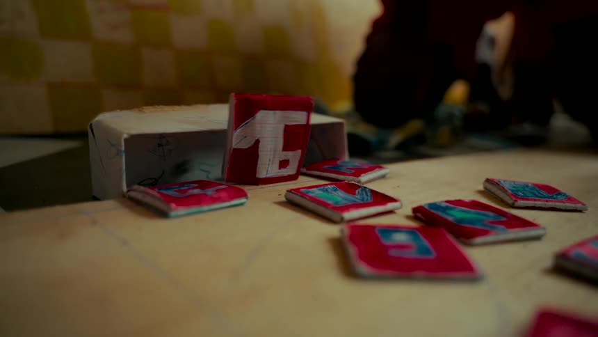 A handmade cardboard game piece with the number fifteen falls over in a stop-motion animation