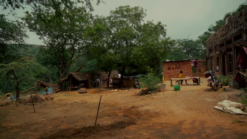 A tranquil scene of daily life unfolds in the courtyard of a rustic Indian village