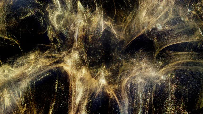 Shimmering golden glitter swirls elegantly in a dark liquid, creating a magical and abstract cosmic cloud