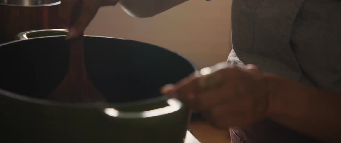 Close-up slow-motion shot of a person stirring a steaming pot in a cozy kitchen
