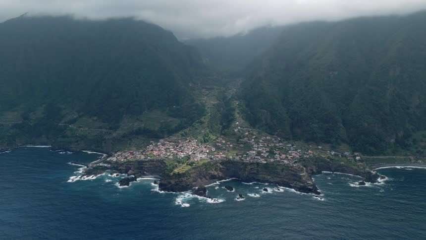 High angle view of the picturesque coastal town of Seixal, nestled between lush green mountains and the Atlantic Ocean in Madeira, Portugal