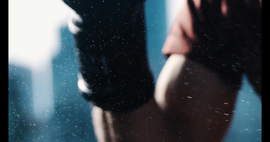 A dramatic slow-motion close-up shows a fine mist of water spraying over a boxer's chin and glove