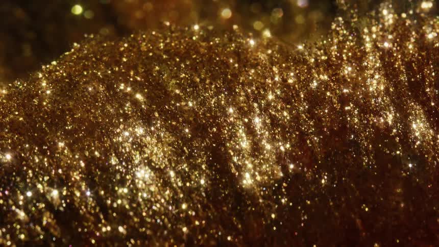 An extreme close-up, macro view of golden glitter sparkles and shimmers in the light, creating a beautiful abstract background