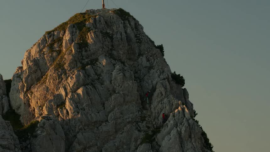 Two climbers scale a mountain peak at dusk