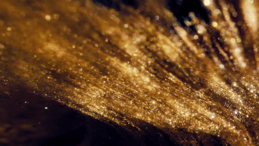 A mesmerizing cascade of sparkling golden glitter flows like a liquid against a dark, abstract background