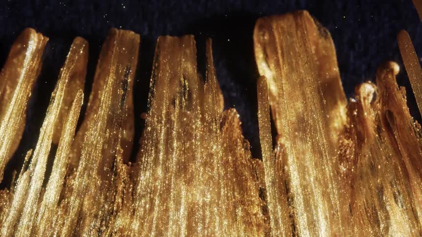 Extreme macro shot of shimmering gold particles flowing upwards along a jagged, crystalline structure