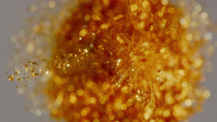 A beautiful top-down macro time-lapse shows a chemical reaction causing golden crystals to form in a flower-like pattern