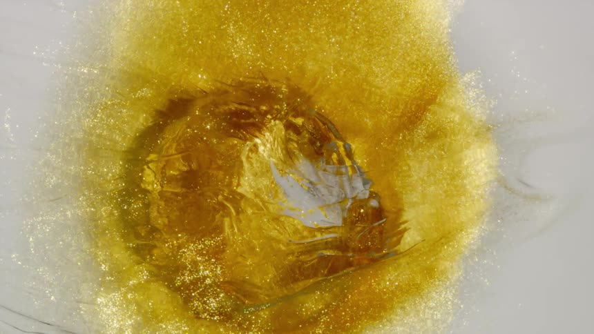 A mesmerizing macro shot of shimmering golden glitter swirling into a hypnotic vortex on a white background