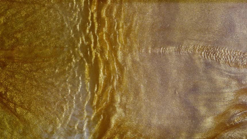 Abstract background of slowly rippling and flowing molten gold with shimmering glitter particles