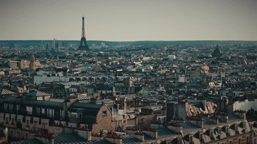 A cinematic establishing shot captures the sprawling cityscape of Paris, with the Eiffel Tower prominent on the horizon