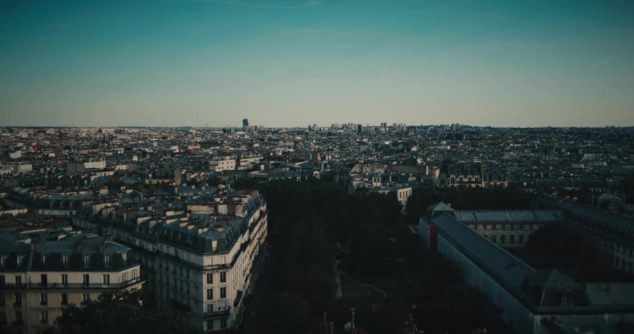 A slow, cinematic aerial flight over the classic rooftops and streets of Paris, France on a beautiful day