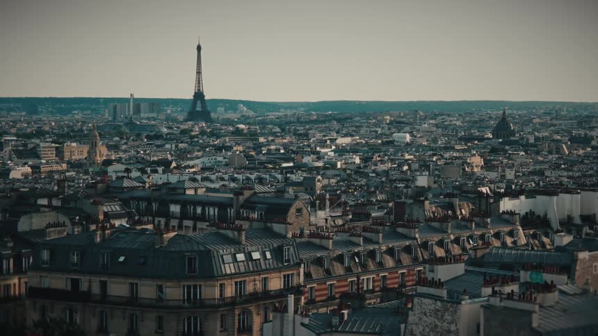 A cinematic aerial dolly shot pulls back over the dense rooftops of Paris, revealing the iconic Eiffel Tower on the horizon
