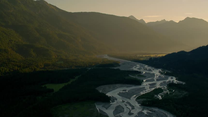 A river runs through a mountain valley at dusk