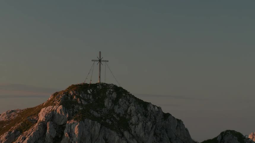 A large metal cross on a mountain at dusk