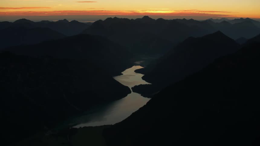 A mountain lake is shown at sunset