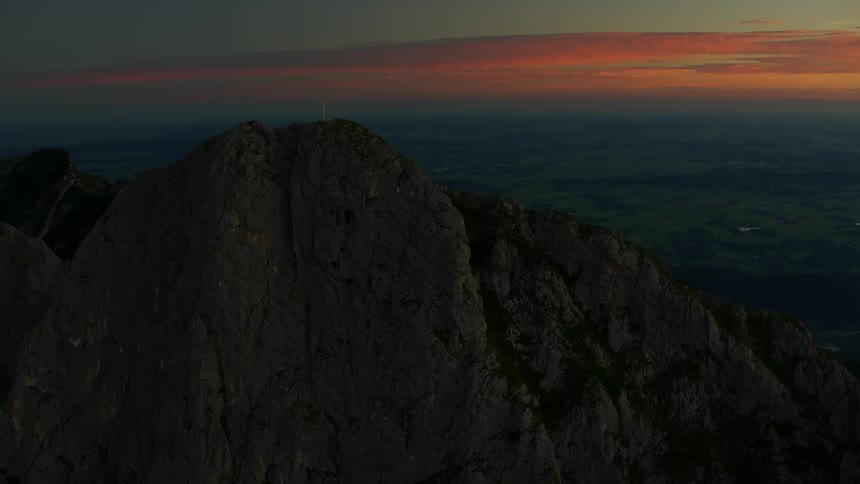 The tall mountain has a cross at the top at dawn