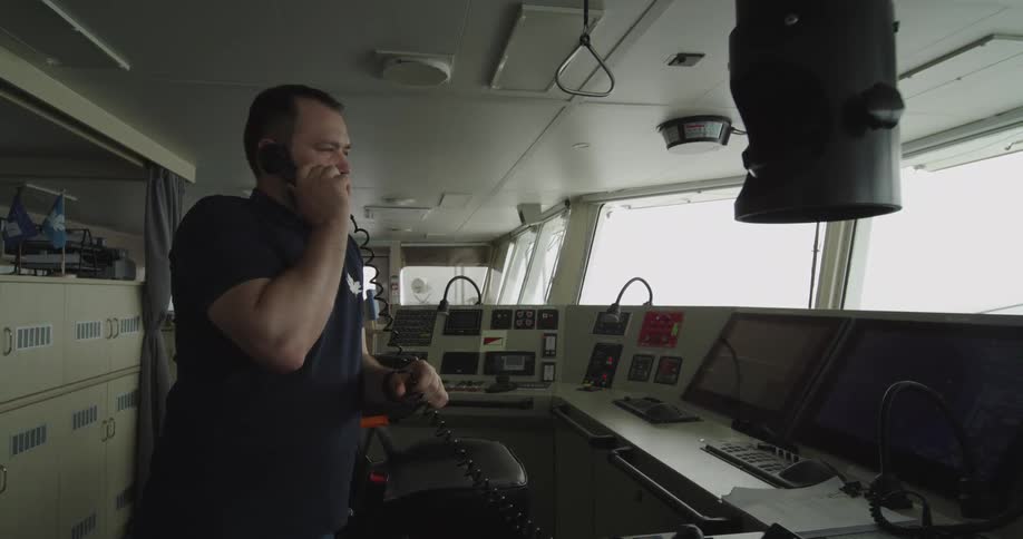 A navigation officer talks on the telephone on the bridge of a cargo ship