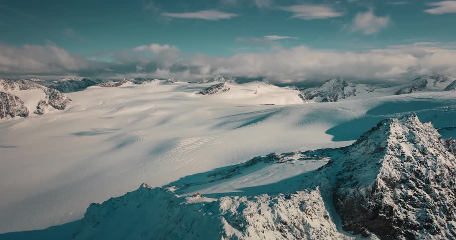 A stunning time-lapse reveals a vast, rocky glacier transforming into a pristine, snow-covered winter landscape from an aerial perspective