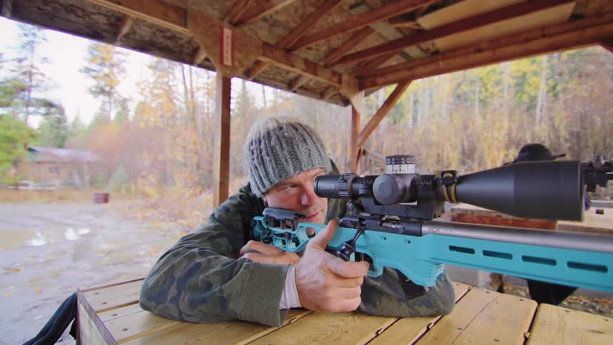 A man in slow motion cycles the bolt and fires a precision rifle at an outdoor shooting range