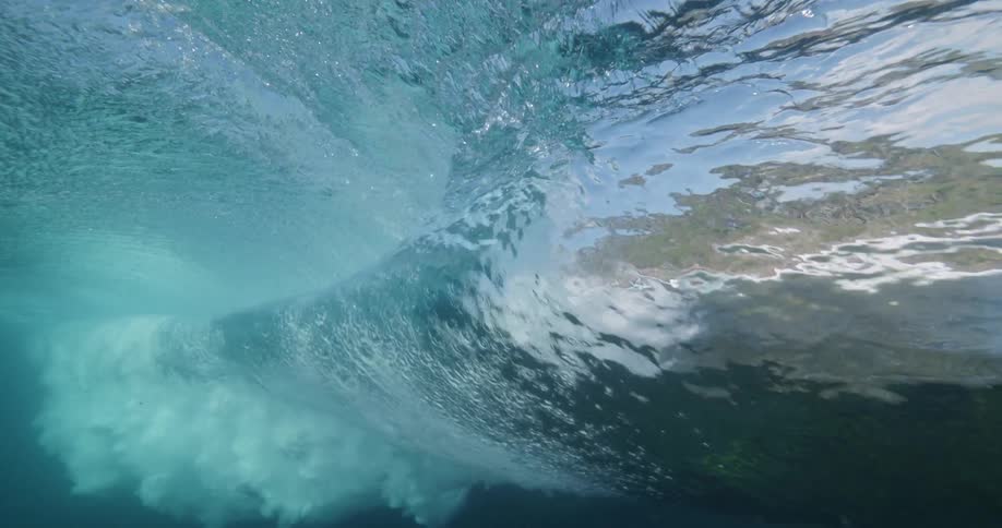 A mesmerizing underwater perspective of a beautiful ocean wave as it curls and crashes in slow motion