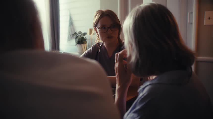 A compassionate female doctor discusses healthcare options with a senior couple during a home visit