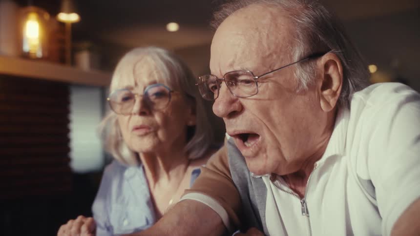 A kind young woman assists a senior couple as they learn to navigate the internet on a laptop in their warm and inviting home