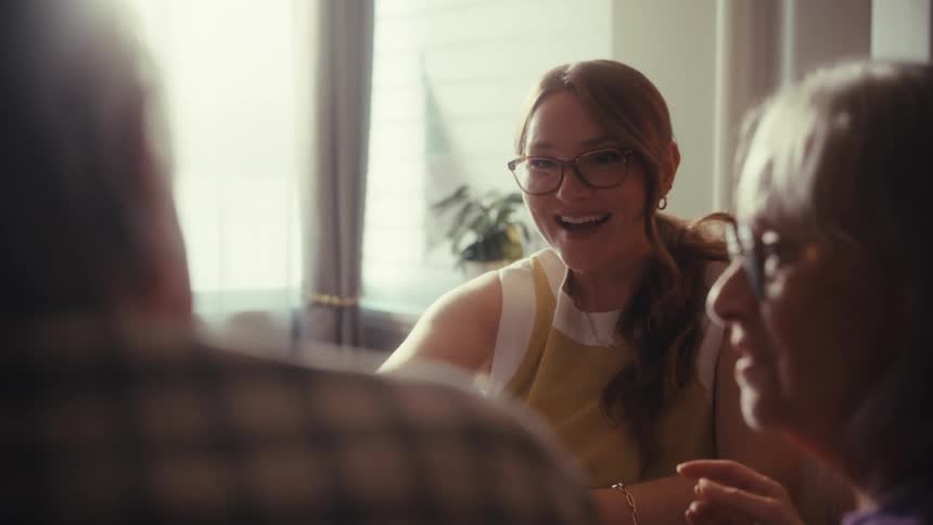 A young female financial advisor happily shakes hands with a senior couple after a successful consultation at a table in a sunlit room