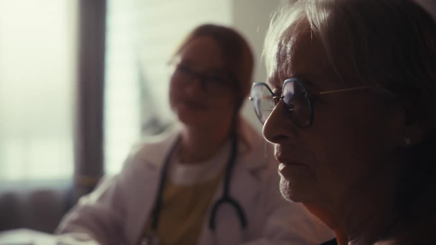 A caring young female doctor consults with a concerned elderly couple in her warmly lit office