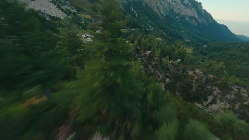 A thrilling first-person-view drone flight over a dense mountain forest, revealing a secluded rustic lodge