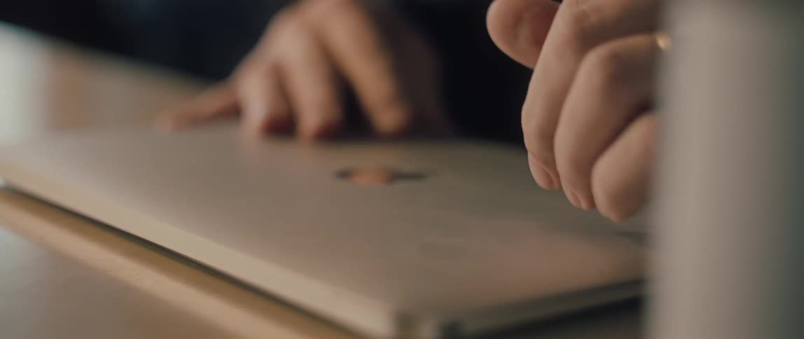 A close-up slow-motion shot shows a person's hands typing on a keyboard and then closing the laptop lid, finishing their work