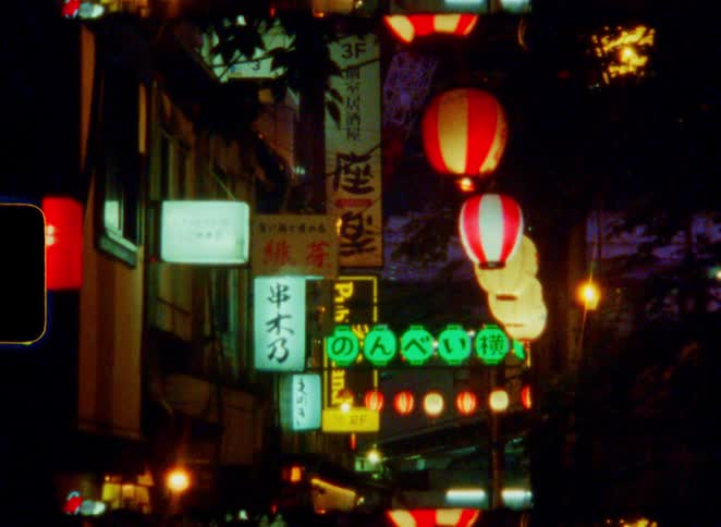 Atmospheric super 8mm film captures the glowing neon signs and paper lanterns of a traditional Japanese alleyway at night
