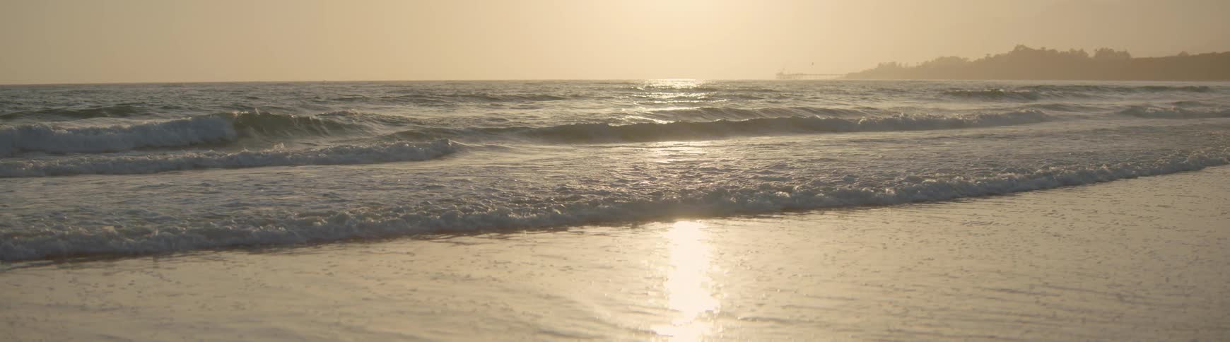 Golden sunset reflects on tranquil ocean waves as they gently roll onto the shore