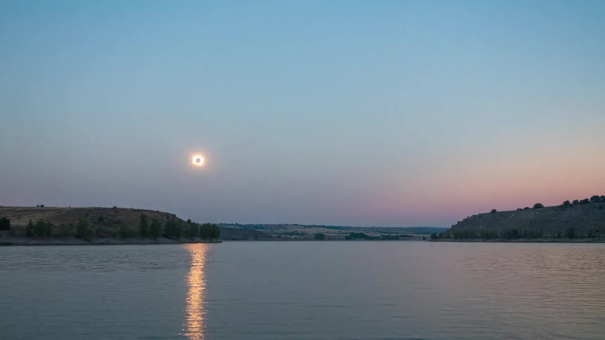 A beautiful timelapse shows an annular solar eclipse setting over a tranquil lake, its reflection shimmering on the water