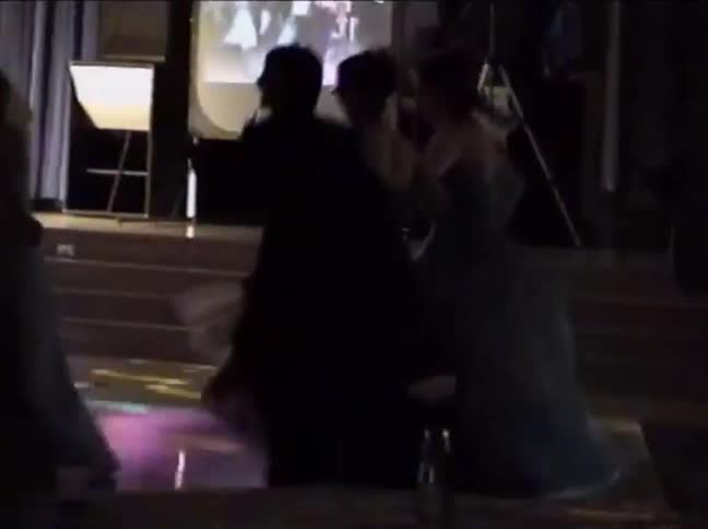 Silhouetted people in formal attire dance energetically at a party in vintage home video footage